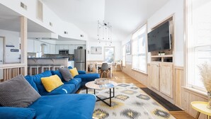 A modern living room with a blue sofa, a coffee table, and a TV. - Steps to Beach, Pool & Tennis in heart of Corolla (Corolla)