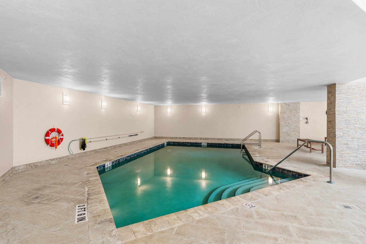 Une piscine intérieure à l’eau claire, équipée d’une bouée de sauvetage et d’une rampe d’accès pour fauteuils roulants.