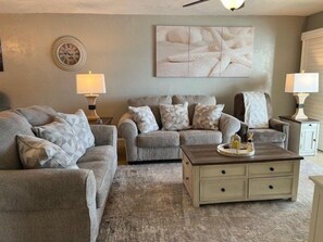 A living room with two sofas, a coffee table, and wall-mounted lamps.