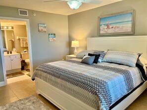 A bedroom with a bed, nightstand, and a painting on the wall.