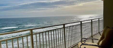 Un balcon avec vue sur l’océan, doté d’une balustrade et d’une table avec des chaises.