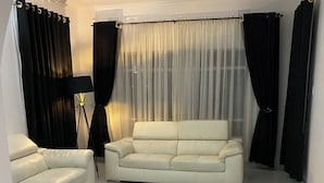 Una sala de estar con un sofá de cuero blanco, un sillón blanco y una lámpara de pie.