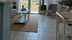 Amplia sala de estar con un gran ventanal corredero que da a un balcón, un sofá, una mesa de centro y un mueble para televisión.