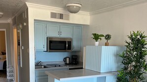 Una cocina compacta con armarios azul claro, un microondas de acero inoxidable y una cafetera.