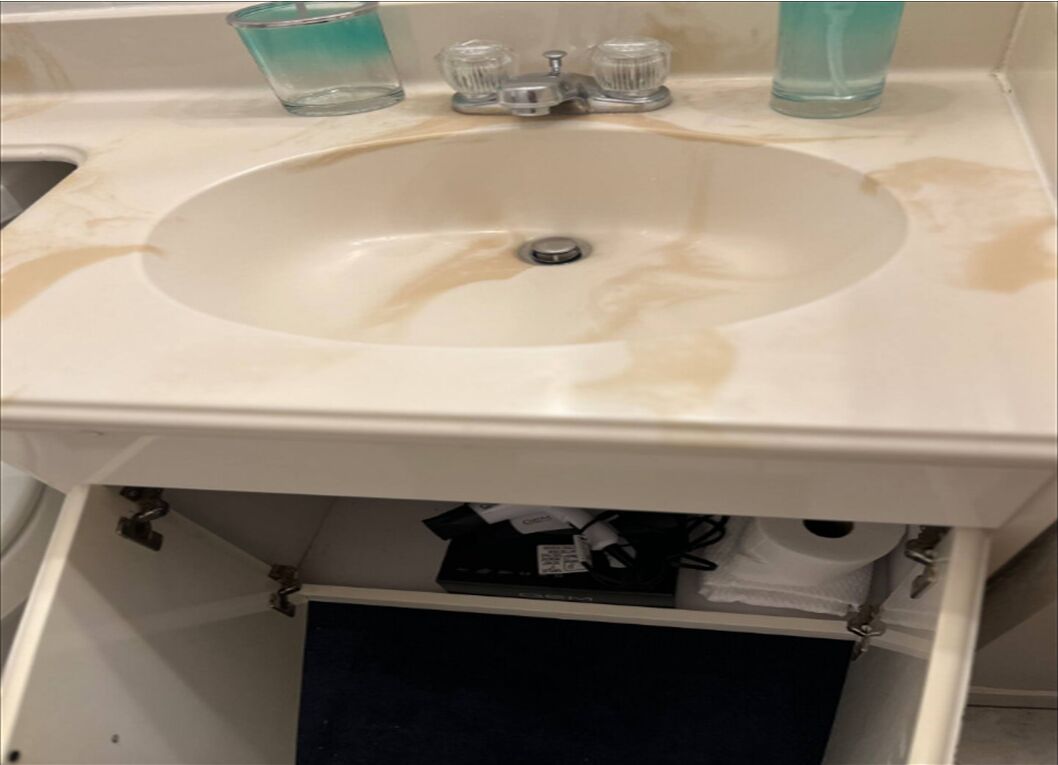 A bathroom sink with a white countertop, a faucet, and a glass soap dispenser.