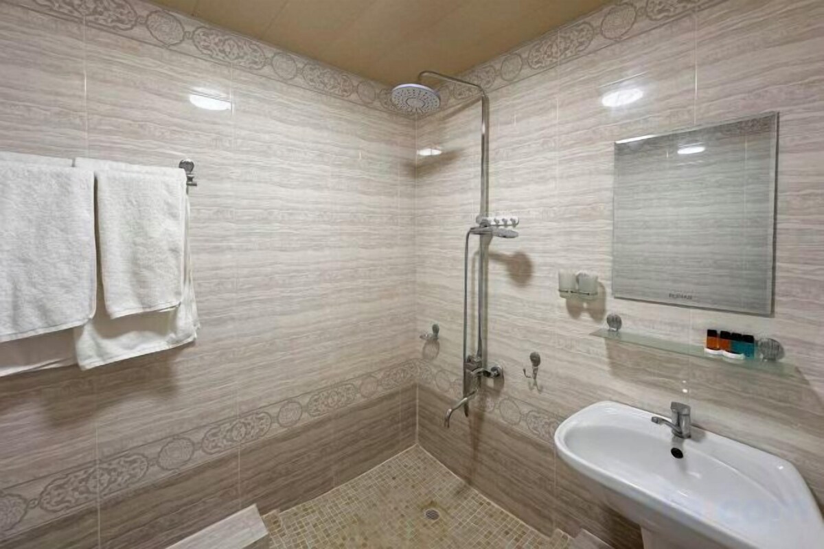 A bathroom with a shower, sink, and mirror.