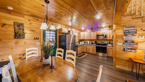 Interior de una cabaña de madera con comedor, cocina y un cartel de bienvenida.