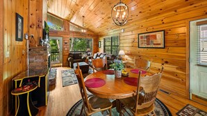 A cozy cabin interior with a dining area, wooden walls, and a stone fireplace. - Always Together Forever: Make Memories That Last (Sevierville)