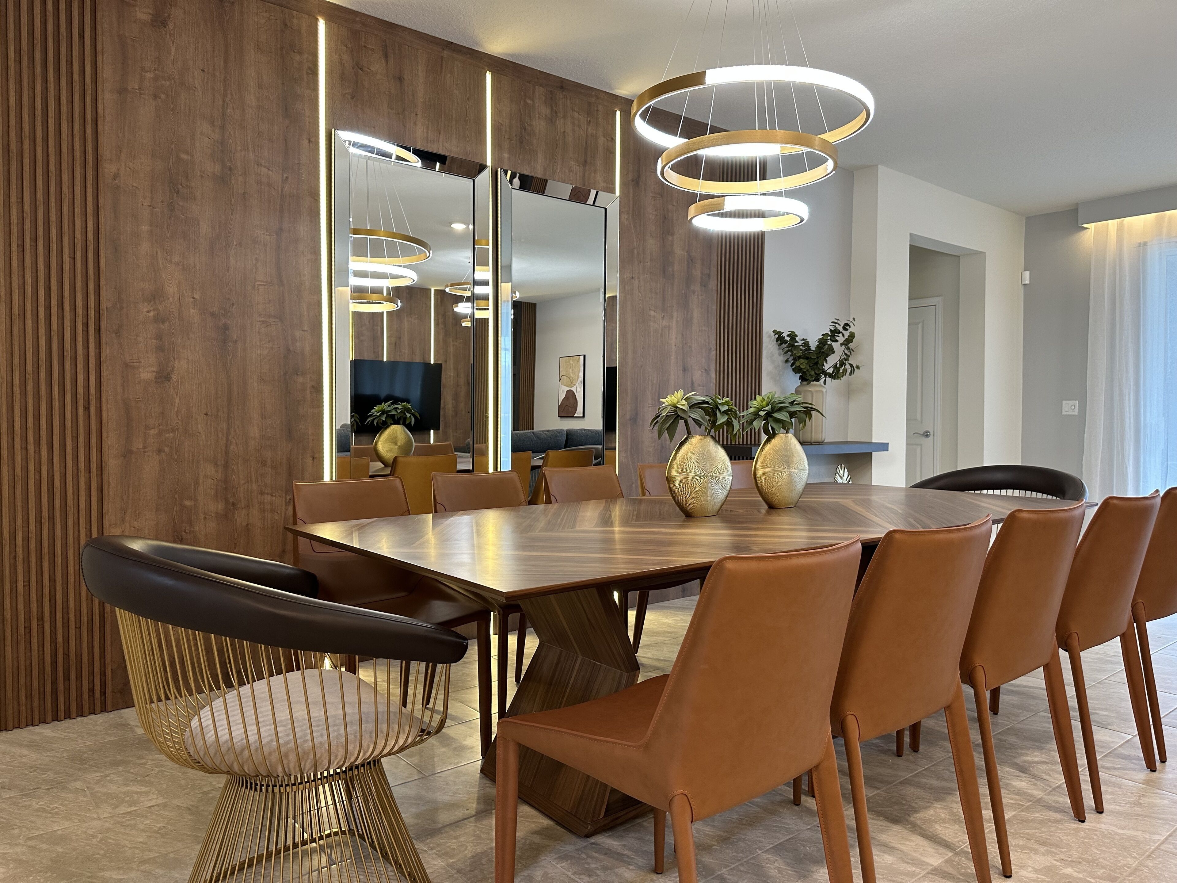 A modern dining room with a wooden table, leather chairs, and a large mirror.