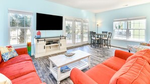 A living room with a TV, a dining table, and orange sofas. - 5 BR Beach House with a Private Pool in Surfside Beach! A Beach Haven (Surfside Beach)