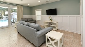 Ein modernes Wohnzimmer mit einem grauen Sofa, einem weißen Couchtisch und einem an der Wand befestigten Fernseher.