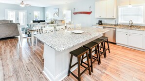 A spacious kitchen with a large island, white cabinetry, and a granite countertop. - 7 BR 2nd Row Beach House with a Private Pool! Aquadisiac  (Surfside Beach)