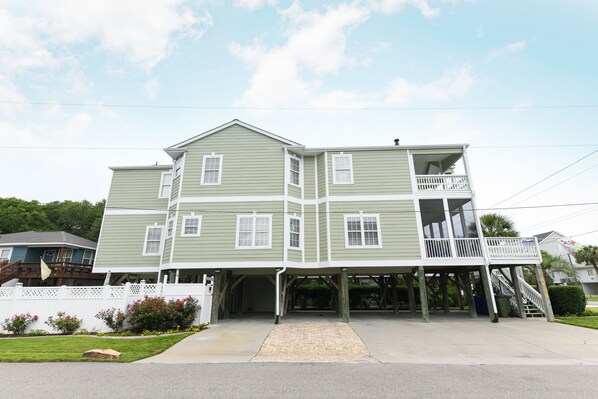 Stunning two-story home with a spacious balcony and covered porch, set behind a charming white picket fence.