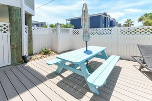 Enjoy al fresco dining on the deck, surrounded by a charming picket fence and a nearby building.