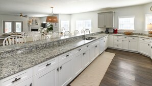 A spacious kitchen with white cabinets, granite countertops, and a large island. - 5 BR 2nd Row Beach House with a Private Pool! Beach Dreams (Surfside Beach)