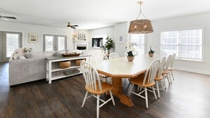 A spacious living area with a dining table surrounded by white chairs, a grey sofa, and a fireplace. - 5 BR 2nd Row Beach House with a Private Pool! Beach Dreams (Surfside Beach)