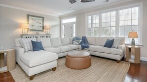 A living room with a sectional sofa, a round ottoman, and a side table with a lamp. - 4 BR Beach House with a Private Pool! It's A Stone Harbor Thing (Surfside Beach)