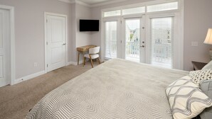 A bedroom with a large bed, a desk, and a TV. - 4 BR Beach House with a Private Pool! It's A Stone Harbor Thing (Surfside Beach)