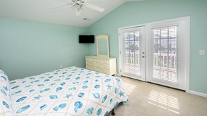 Ein Schlafzimmer mit einem Bett, einer Kommode, einem Deckenventilator und einem Fernseher an der Wand.