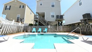 A swimming pool with a wooden deck and three blue chairs. - 2nd Row 5 BR Beach House with a Private Pool! Sale Away (Surfside Beach)