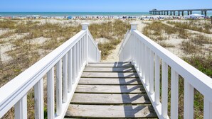 A wooden staircase leading to a beach with a pier in the background. - Oceanfront 5 BR Beach House with a Private Pool! La Dolce Vita (Surfside Beach)