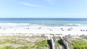 A beach with a wooden boardwalk leading to the water, sandy beach, and umbrellas. - Oceanfront 8 BR Beach House with a Private Pool! The Emerald (Surfside Beach)