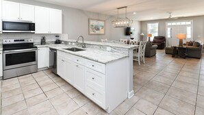 Una cocina moderna con armarios blancos, microondas integrado y una isla grande con pileta.