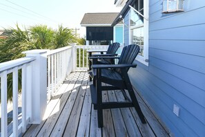 A wooden deck with two chairs and a table, overlooking a beach with palm trees. - 2nd Row 5 BR Pet Friendly Beach House with a Private Pool! Margaritaville  (Surfside Beach)
