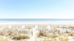Une plage avec des clôtures en bois et de l’herbe sèche au premier plan.