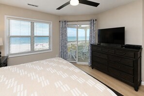 A bedroom with a bed, a TV, a dresser, and a balcony with a view of the beach. - Oceanfront 4 BR Beach House with Shared Pool! Portofino II 313B. (Surfside Beach)