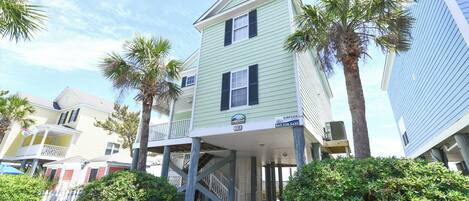 A two-story building with a covered porch and a staircase leading to the second floor.