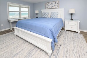 A bedroom with a large bed, a window with a view, two bedside tables with lamps, and a headboard with a floral design.