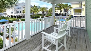 A wooden deck with white railings, a pool, and a view of neighboring houses. - Oceanfront 4 BR Beach House with Shared Pool! Portofino II 313B. (Surfside Beach)