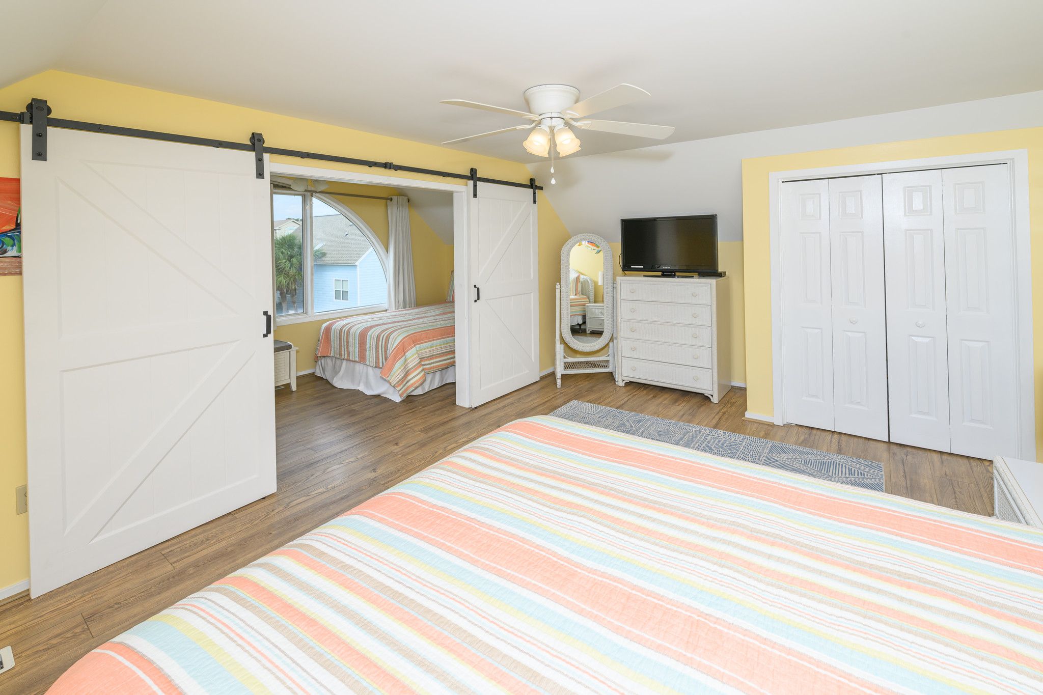 A bedroom with a bed, a dresser, a television, and a wardrobe.