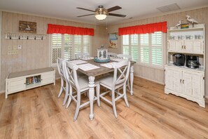 A dining area with a wooden table and chairs, a ceiling fan, and a cabinet with kitchen appliances. - 3 BR Beach House in Surfside Beach with Shared Pool!  Sea Bridge 1015 (Surfside Beach)