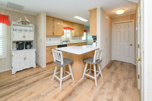 A kitchen with wooden cabinets, a white countertop, and two bar stools. - 3 BR Beach House in Surfside Beach with Shared Pool!  Sea Bridge 1015 (Surfside Beach)