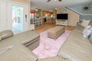 A living room with a sofa set, a wicker ottoman, and a television. - 3 BR Beach House in Surfside Beach with Shared Pool!  Sea Bridge 1015 (Surfside Beach)