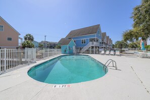 A swimming pool with a depth marker, surrounded by a white fence, with houses in the background. - 3 BR Beach House in Surfside Beach with Shared Pool!  Sea Bridge 1015 (Surfside Beach)