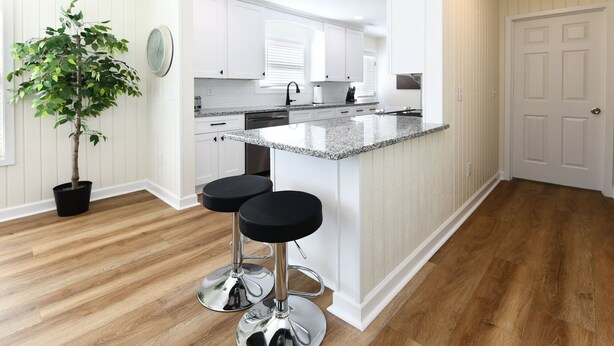 A modern kitchen with white cabinetry, a granite countertop, and two black bar stools. - 2nd Row, 3 BR Beach House with Shared Pool in Surfside Beach! Sea Bridge 1018 (Surfside Beach)