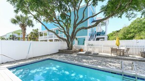 A swimming pool with a white fence, a tree, and a building in the background. - Pet Friendly 6 BR Beach House with a Private Pool in Surfside Beach! Sea La Vie  (Surfside Beach)
