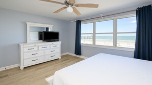 A bedroom with a bed, a dresser, a television, and a window with a view of the beach. - Pet-Friendly Oceanfront 4 BR Beach House in Surfside Beach! Sunny Delight (Surfside Beach)