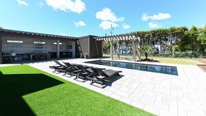 A modern outdoor patio with a swimming pool, sun loungers, and a pergola. - 4 BR 2nd Row Beach House with a Private Pool! California Dreamin' (Garden City)