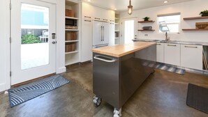 A modern kitchen with a central island, white cabinetry, and a view to the outside. - 4 BR 2nd Row Beach House with a Private Pool! California Dreamin' (Garden City)