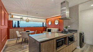 Une cuisine moderne dotée d’un îlot central, d’un four encastré et d’une grande fenêtre offrant une vue dégagée.