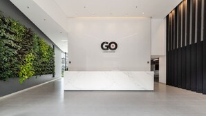 Un espace d’accueil moderne avec un comptoir en marbre, le logo de « GO Living & Suites » et un jardin vertical sur le côté gauche.