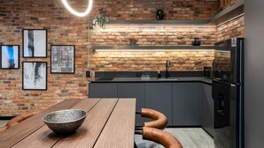 Una cocina moderna con paredes de ladrillo visto, una mesa de comedor de madera y un horno empotrado.
