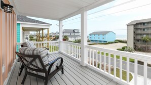 A covered porch with a view of the ocean and neighboring buildings. - 7 BR Beach House with a Private Pool in Surfside Beach! Salty Beaches. (Surfside Beach)