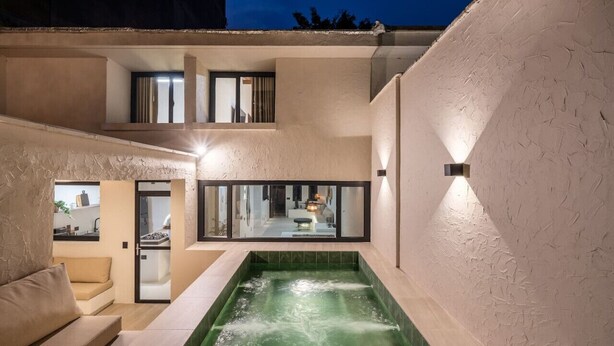 Un espace spa moderne doté d’un jacuzzi, d’un canapé et d’une cuisine, le tout visible à travers une porte en verre.