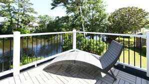 A wooden deck with a white railing, a wicker chair, and a view of a lake and trees. - 2 Bedrooms Townhouse in Surfside Beach! Dottie's Place (Surfside Beach)