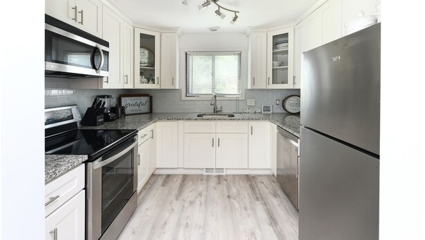 A modern kitchen with white cabinets, stainless steel appliances, and a granite countertop. - 2 Bedrooms Townhouse in Surfside Beach! Dottie's Place (Surfside Beach)